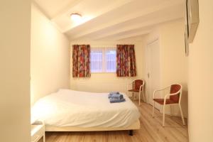 1 dormitorio pequeño con 1 cama y 2 sillas en De Specht en Bergen