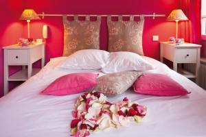 Una cama con almohadas rosas y blancas y flores. en Le Kléber Hôtel, en Estrasburgo
