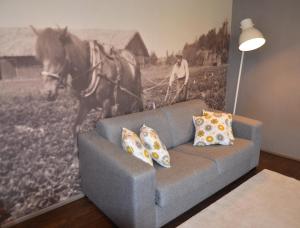 un sofá en una sala de estar con una foto de un caballo en Tammiston Apartments, en Naantali