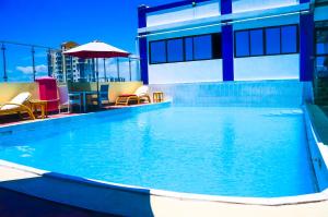 a large swimming pool with chairs and an umbrella at Sheratton Regency Hotel in Mombasa