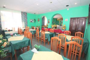 ein Restaurant mit grünen Wänden, Tischen und Stühlen in der Unterkunft Willa Ewa in Jantar
