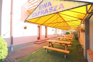 a row of wooden picnic tables under a yellow umbrella at Willa Ewa in Jantar