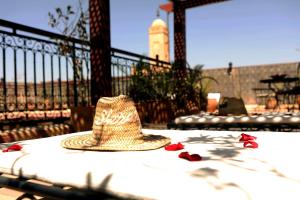 a straw hat sitting on a table with red flowers at Riad Hotel Sherazade in Marrakech