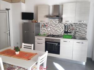 una cucina con armadi bianchi, tavolo e piano cottura di appartamento Manzoni a Porto Cesareo