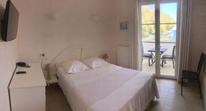 a bedroom with a white bed and a balcony at L'Isula Rossa in LʼÎle-Rousse