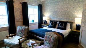 a bedroom with a bed and a chair and windows at The Little Inn at Grasmere in Grasmere