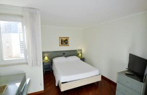 a white bedroom with a bed and a television at Zodiacus Residence in Bari