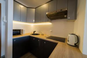 a kitchen with black cabinets and a sink and a microwave at Apartament51 in Mikołajki