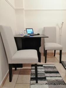 een bureau met een laptop en 2 witte stoelen bij Luxurious Apartment in Veria