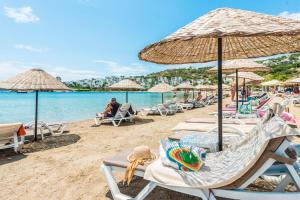 a beach with chairs and umbrellas and the ocean at Costa Bitezhan Hotel - All Inclusive in Bitez
