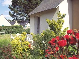 ein weißes Haus mit Stühlen und Blumen im Hof in der Unterkunft Lagrange Vacances Les Maisonnettes in Le Pouliguen