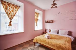 Schlafzimmer mit rosa Wänden, einem Bett und zwei Fenstern in der Unterkunft Sweet Home in Kamjanez-Podilskyj
