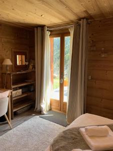a bedroom with a bed and a desk and a window at Chez Fred et Carine (Petit-déjeuner bio inclus) in Auron