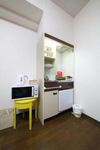 una piccola cucina con tavolo giallo e forno a microonde di Exsaison Shirokita 307 ad Osaka