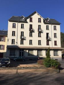 a large white building with cars parked in a parking lot at Magnifique et lumineux appartement au cœur du Sancy in Saint-Nectaire