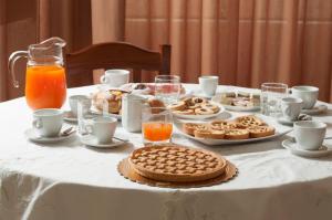 a table with a white table cloth with cookies and orange juice at B&B Villa Roma in Piazza Armerina