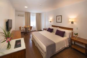 a hotel room with a large bed and a table at Hotel Saint George in Puerto Iguazú