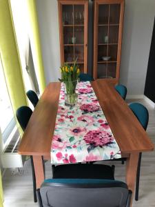 a wooden table with a vase of flowers on it at Krakowska Apartamenty z Ogrodem i Parkingiem in Szczecin +11 photos