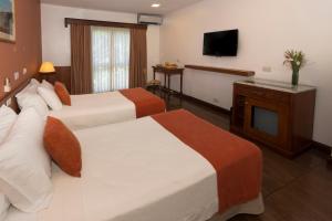 a hotel room with two beds and a flat screen tv at Hotel Saint George in Puerto Iguazú