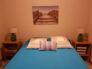 a bedroom with a bed with blue sheets and two lamps at Our relaxing holiday home in Mosteiros
