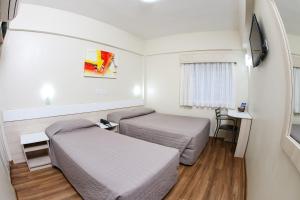 a small room with two beds and a tv at Hotel Express Rodoviária in Porto Alegre