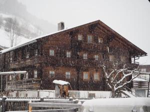 een groot houten gebouw met sneeuw erop bij Ferienhaus Innerkienzerhof - Urlaub am Bauernhof in Matrei in Osttirol