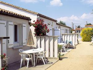 un patio avec des tables et des chaises à côté d'un bâtiment dans l'établissement Lagrange Vacances Les Maisons de Saint Georges, à Saint-Georges-de-Didonne