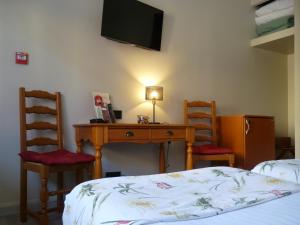 a bedroom with a desk and two chairs and a bed at The Originals Boutique, Hôtel Clos Sainte Marie, Nevers in Nevers