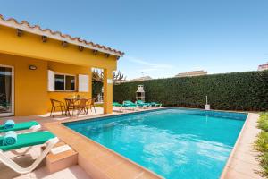 a swimming pool with chairs and a house at Villa Aries in Cala en Forcat