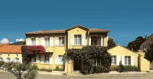 duży żółty dom po stronie ulicy w obiekcie Hôtel Lou Paouvadou w miejscowości Sainte-Maxime