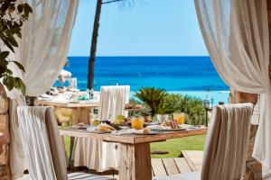 a table with food and the ocean in the background at La Villa Del Re - Adults Only - Small Luxury Hotels of the World in Castiadas