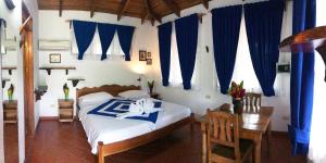 a bedroom with a bed and a table and blue curtains at Hotel de Campo Caño Negro in Caño Negro +110 photos