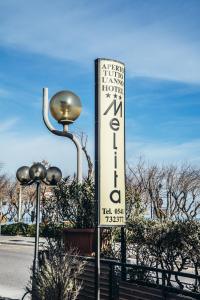 una señal para un hotel con luz de la calle en Hotel Melita en Rímini