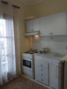 uma cozinha com armários brancos, um fogão e uma janela em Sofia's House em Litochoro