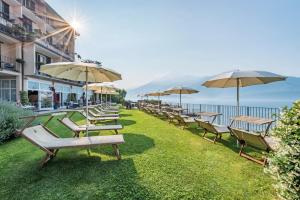 a row of chairs and umbrellas on the grass at Hotel Regina in Gravedona