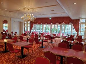 a dining room with tables and chairs and a chandelier at Hotel Kaiserhof in Lübeck