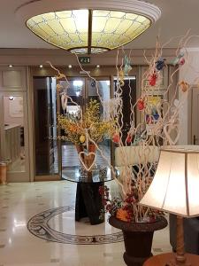 un vestíbulo con una mesa con flores y una lámpara en Hotel Palazzo Lovera, en Cuneo