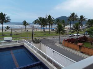 een balkon met uitzicht op het strand en een zwembad bij Pousada e Restaurante Cantinho Oriental in Bertioga