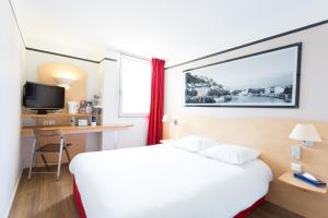 um quarto de hotel com uma cama, uma secretária e uma televisão em Hotel inn Grenoble Eybens Parc des Expositions Ex Kyriad em Eybens