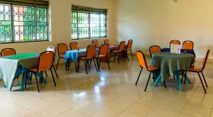 a dining room with tables and chairs and windows at Hotel Atlantica in Fort Portal