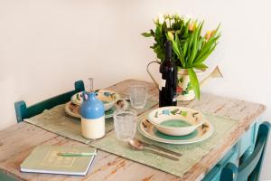 a wooden table with plates and a vase of flowers at TorreParadiso Holidays in Polignano a Mare