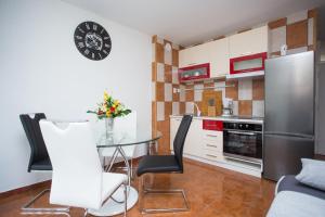 uma cozinha com uma mesa de vidro e um frigorífico de aço inoxidável em Apartmani Maras em Split