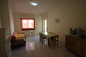 ein Wohnzimmer mit einem Tisch und einem TV in der Unterkunft Appartamenti San Foca in San Foca