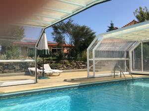 a swimming pool with a pergola and a house at Casa Vale de Azibo in Macedo de Cavaleiros