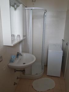 La salle de bains blanche est pourvue d'un lavabo et d'une douche. dans l'établissement Residence Alba, à Riccione