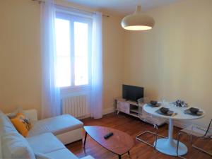 a living room with a white couch and a table at Sémard in Brive-la-Gaillarde