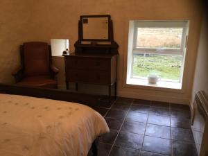 a bedroom with a bed and a mirror and a chair at Comraich in Tokavaig