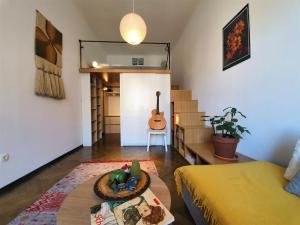 a room with a bed a table and a guitar at Cosy Ljubljana Loft in Ljubljana
