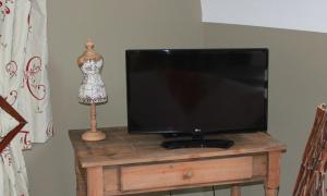 a flat screen tv sitting on a wooden table with a mannequin at A l'ombre du noyer in Fernelmont