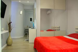 1 dormitorio con cama roja y jarrón en Studio NATASHA in the area of Kallithea, en Atenas